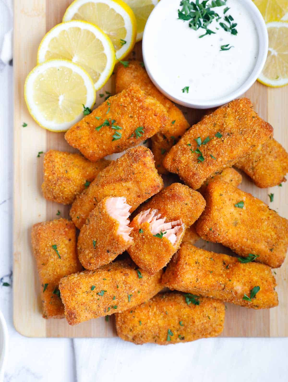 Crispy baked salmon fish fingers with dipping sauce and lemons.