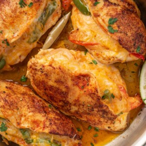 A pan full of seared chicken stuffed with peppers.