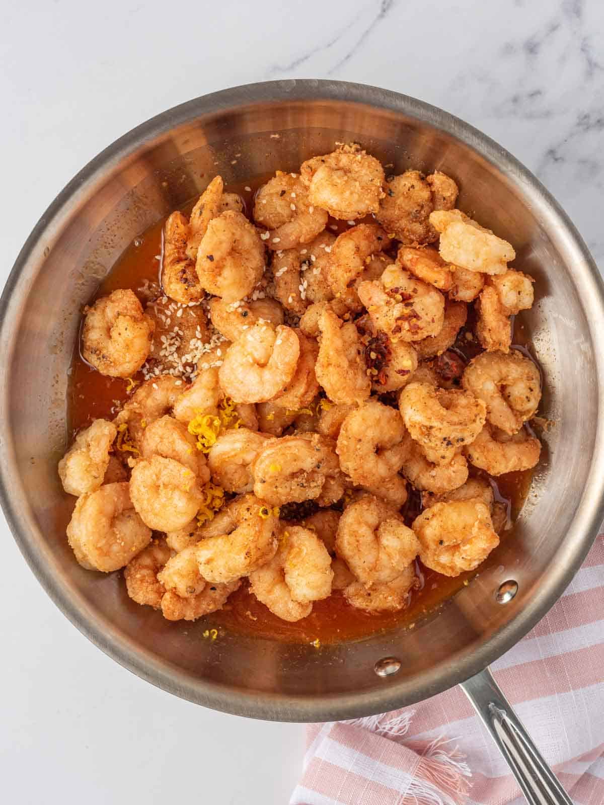 Tossing spicy fried shrimp with firecracker shrimp sauce in a pan.