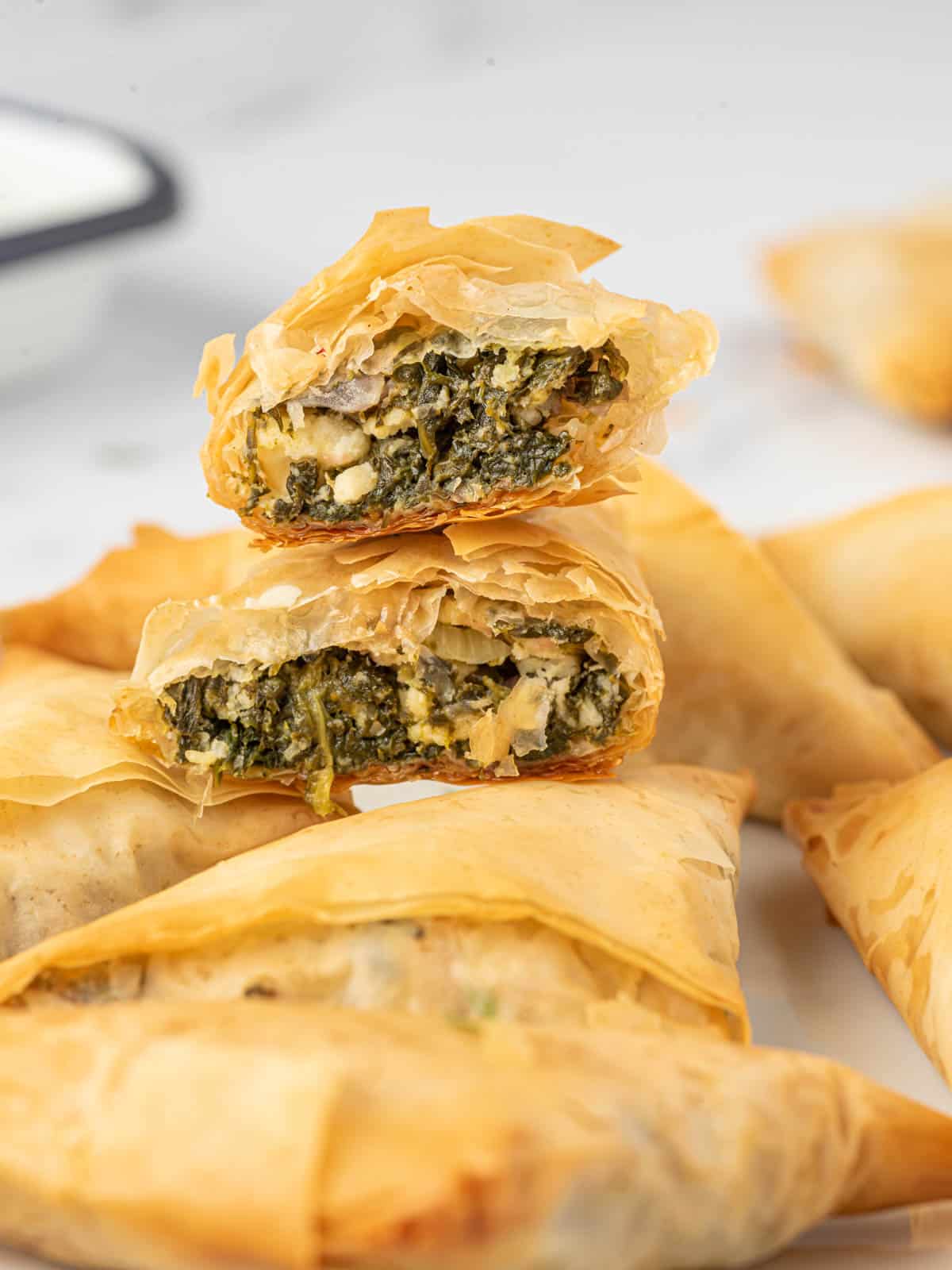 Handheld greek spinach pie cut in half and stacked on a platter.