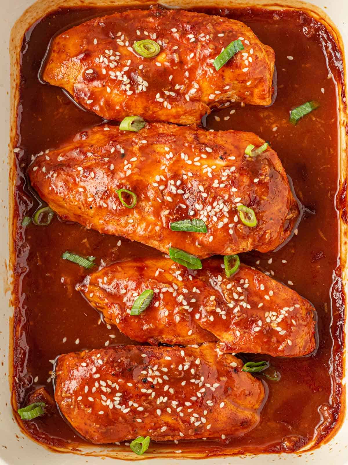 Garnished honey sriracha chicken in a baking dish.