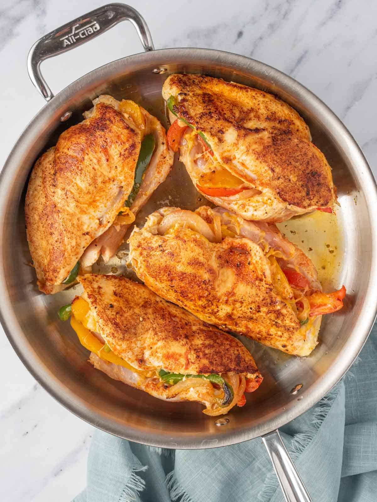 Searing chicken stuffed with peppers in a skillet.