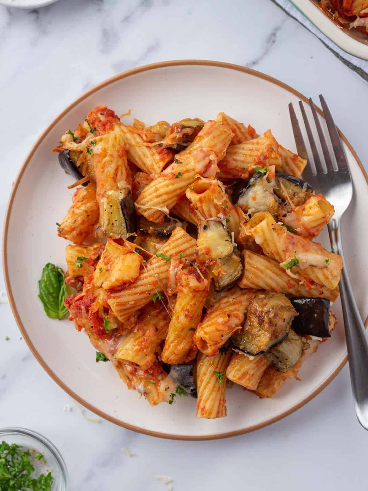 A plate with a pile of spicy eggplant casserole and a fork.