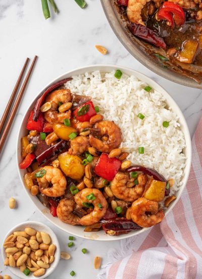 Kung pao shrimp recipe in a bowl with rice and chopsticks on the rice.