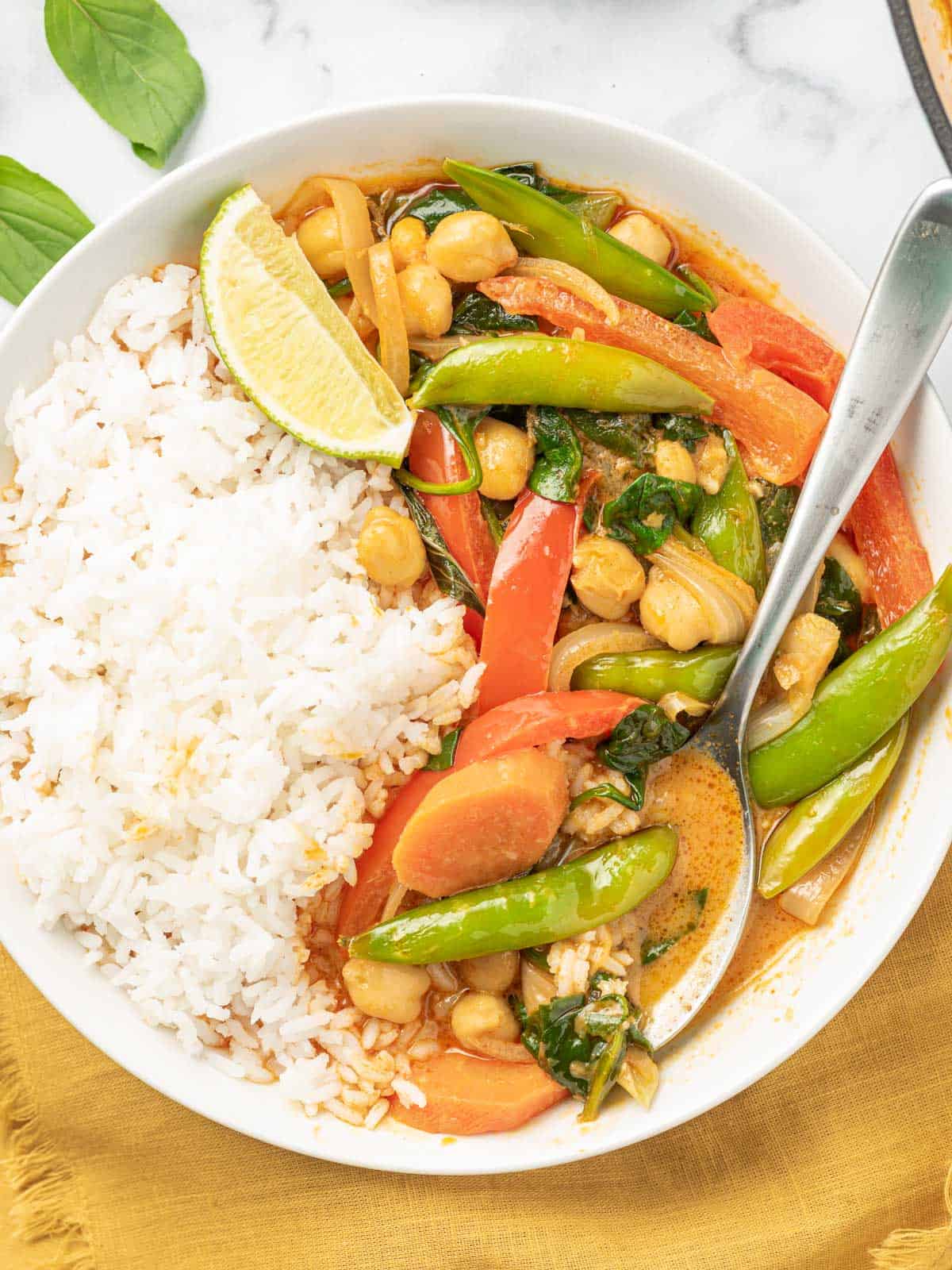 Red thai curry in a bowl with rice and a spoon.