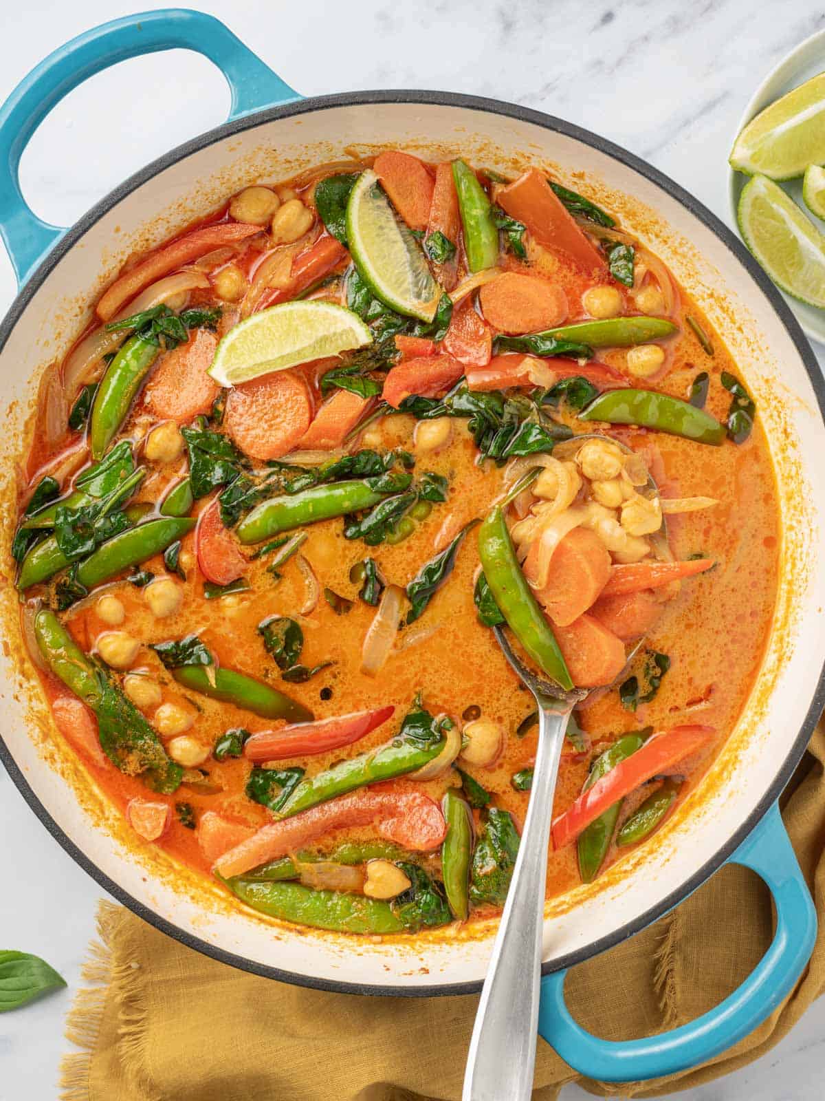 Thai curry with vegetables in a pot with a serving spoon.