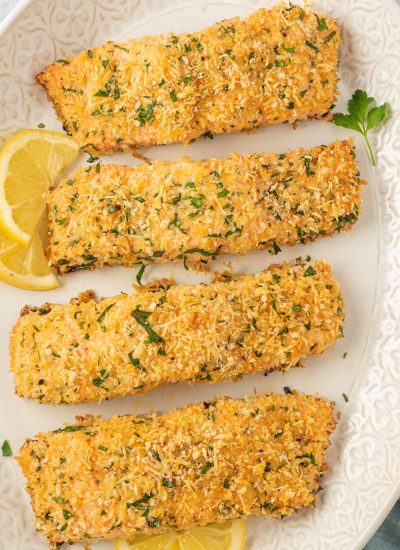 Crispy baked salmon fillets on a platter with lemon slices.