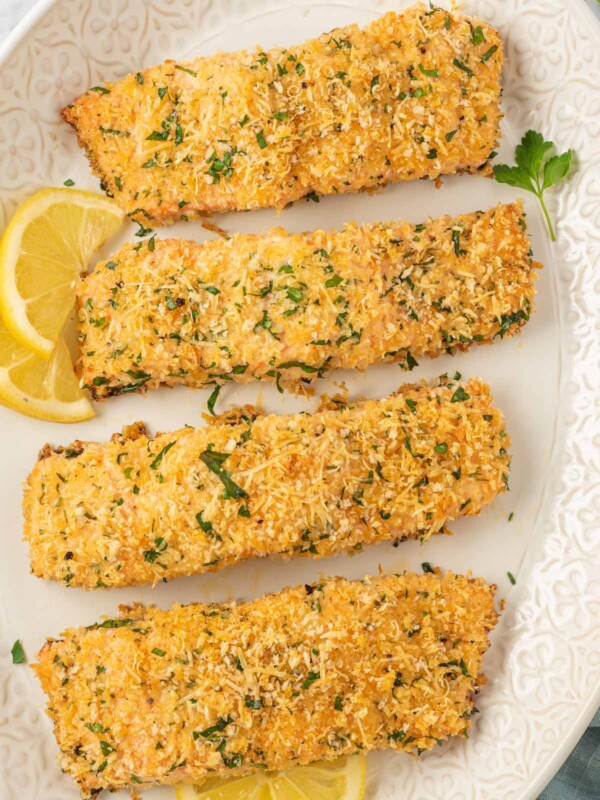 Crispy baked salmon fillets on a platter with lemon slices.