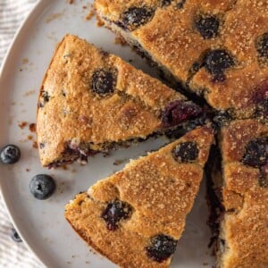 Sliced of easy breakfast cake on a serving platter with fresh blueberries.