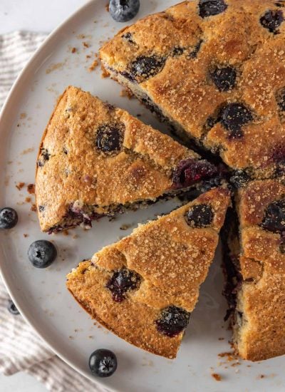 Sliced of easy breakfast cake on a serving platter with fresh blueberries.