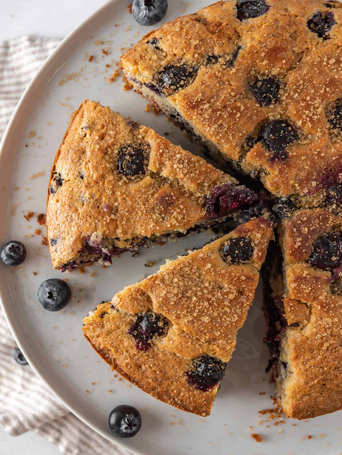 Sliced of easy breakfast cake on a serving platter with fresh blueberries.