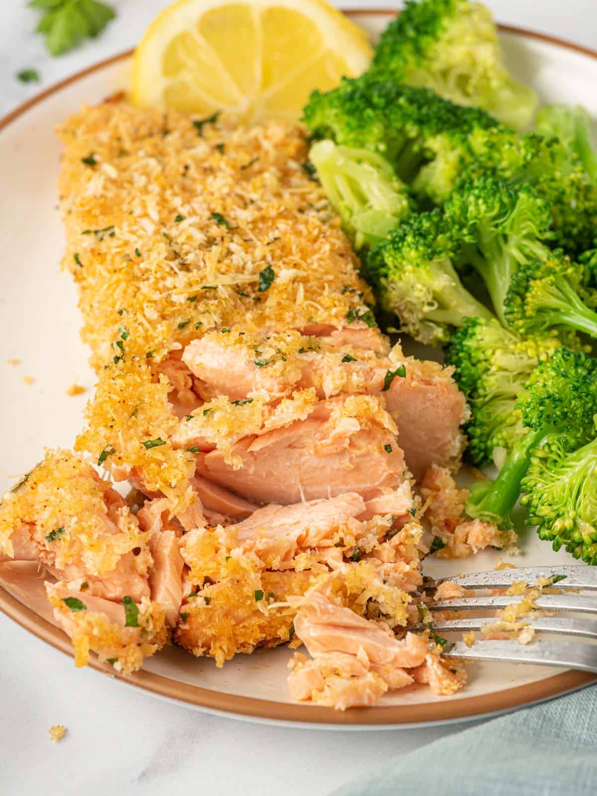 A fork flakes off parmesan crusted salmon recipe.