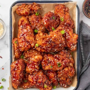 Chicken tenders coated with gochujang sauce on a tray.