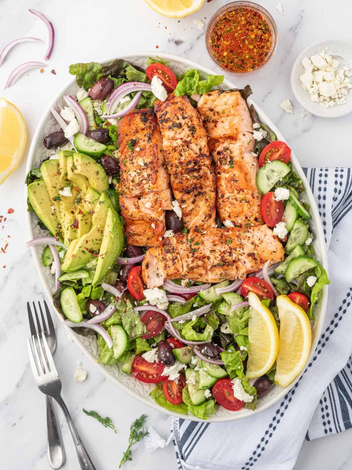 A platter of grilled salmon salad with forks.