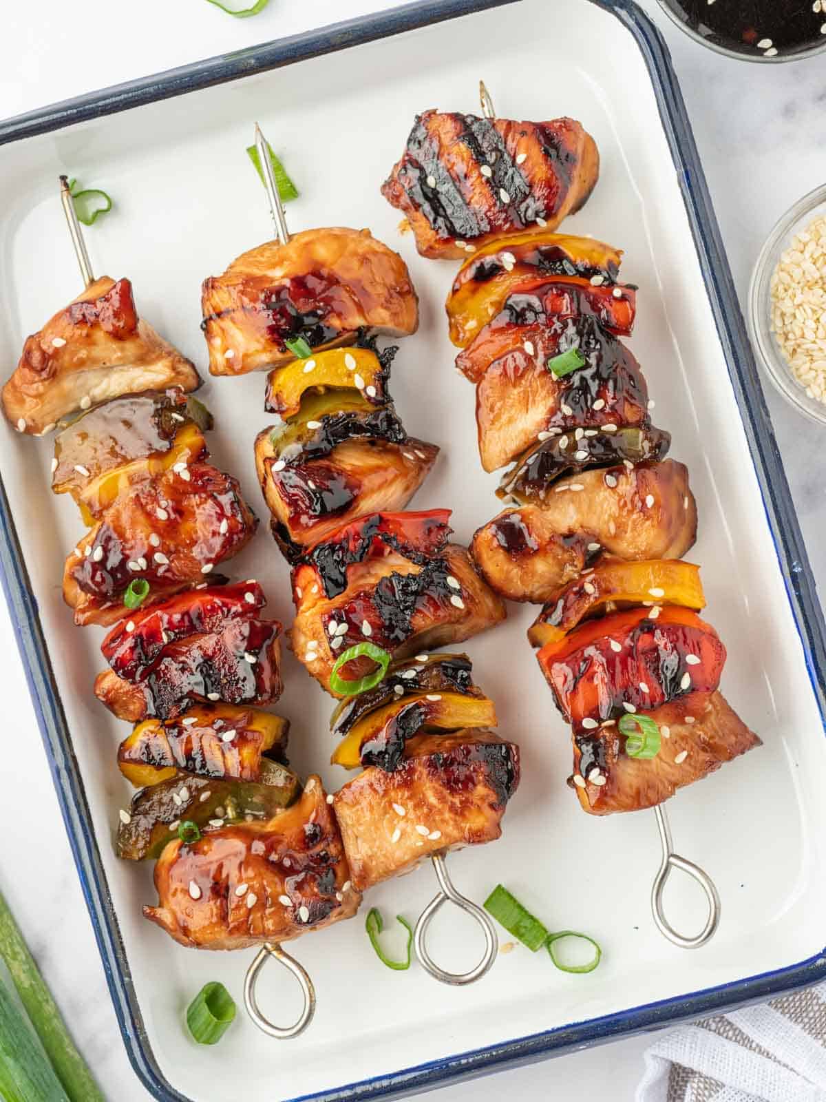 Marinated chicken teriyaki skewers on a platter.