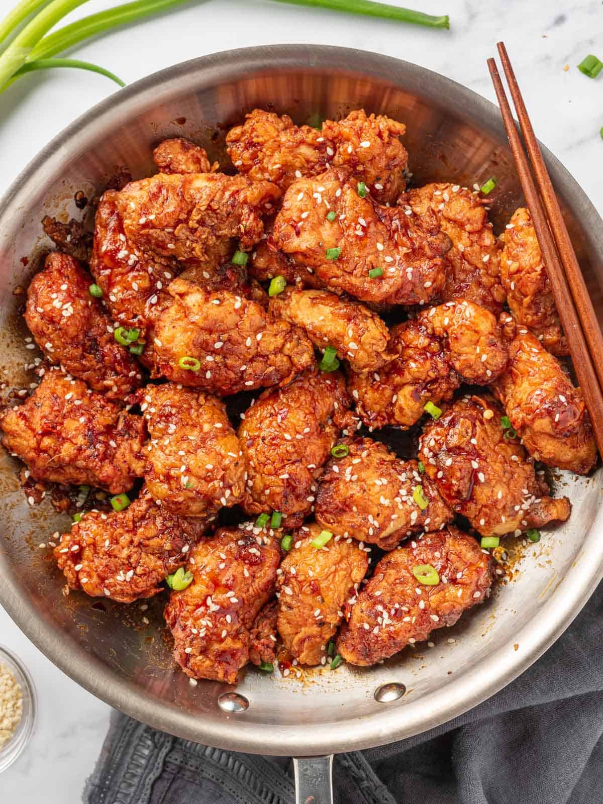 A pot with korean crispy fried chicken and chopsticks.