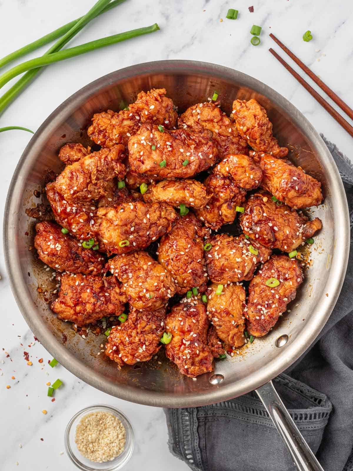 Crispy fried korean chicken with spicy sauce in a skillet.