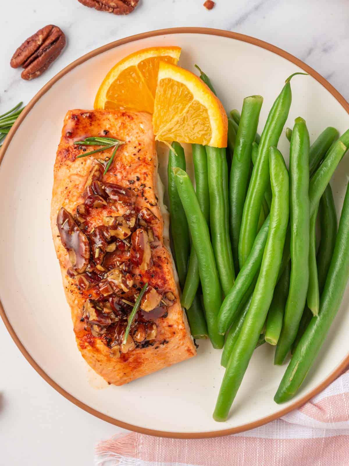 A plate with green beans and salmon with pecans.