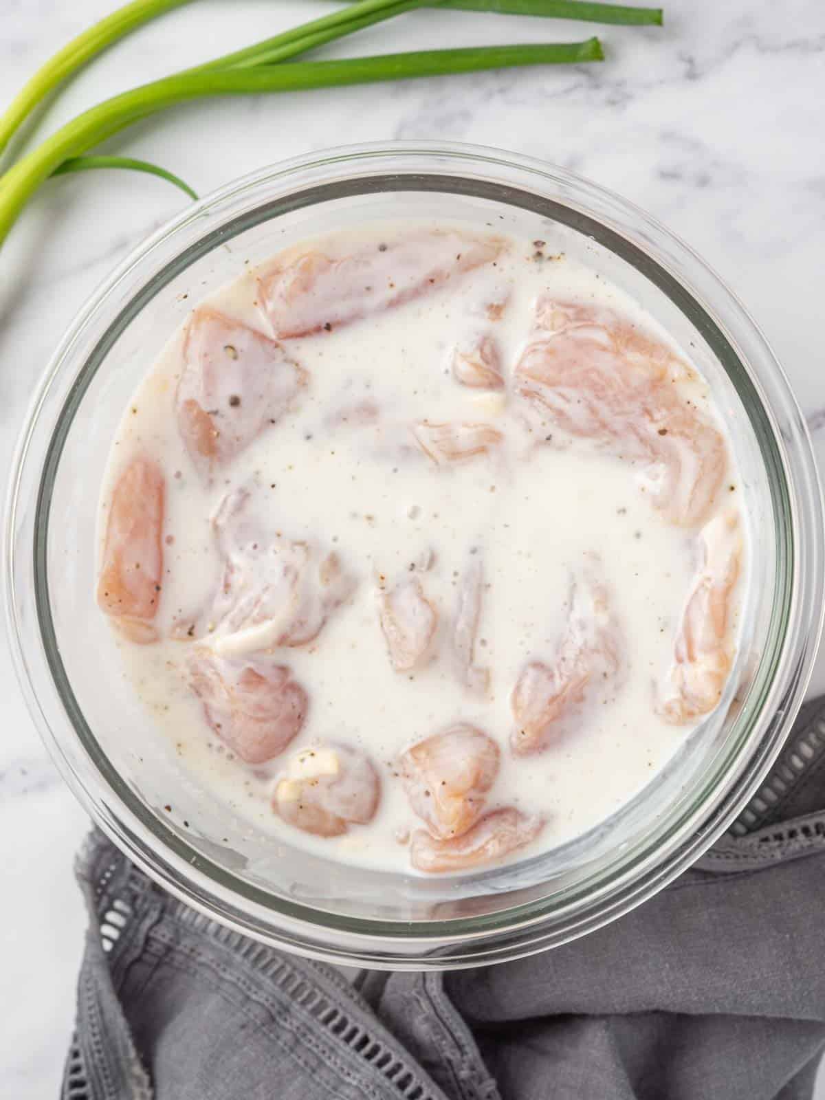 Marinating korean chicken tenders in a bowl of buttermilk.