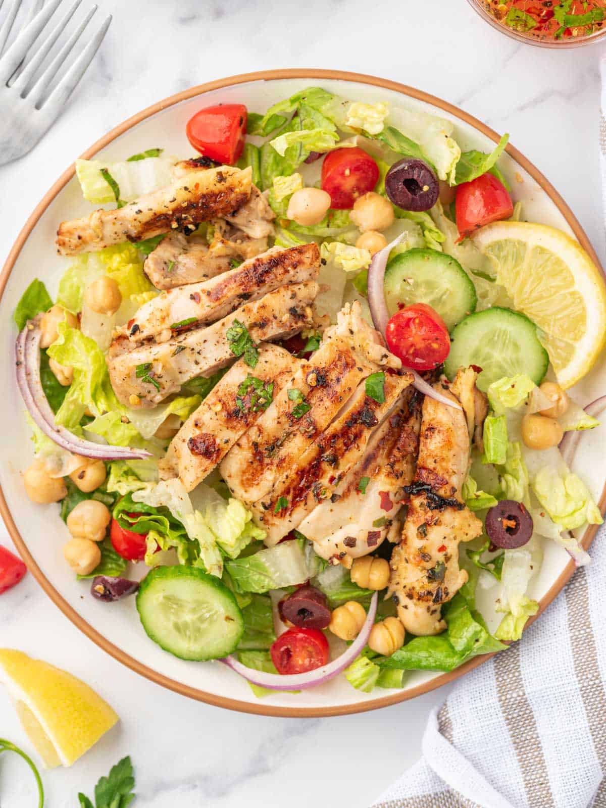 A serving of healthy salad with chicken on a plate.