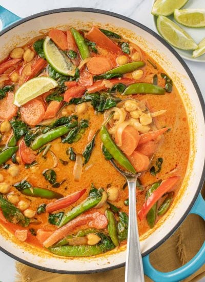 Serving red curry with vegetables from a pot.