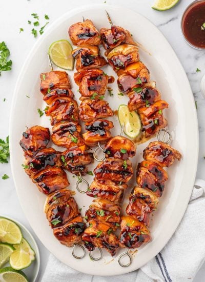 Honey bbq chicken kabobs on a platter with lime wedges.