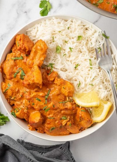 A fork rests on a bowl of healthy chicken tikka masala served with rice.