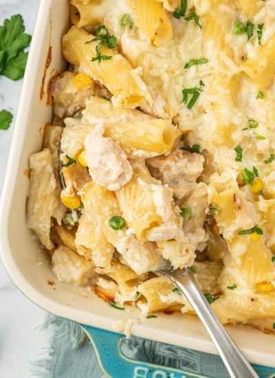 A spoon scoops a serving of cheesy tuna bake.