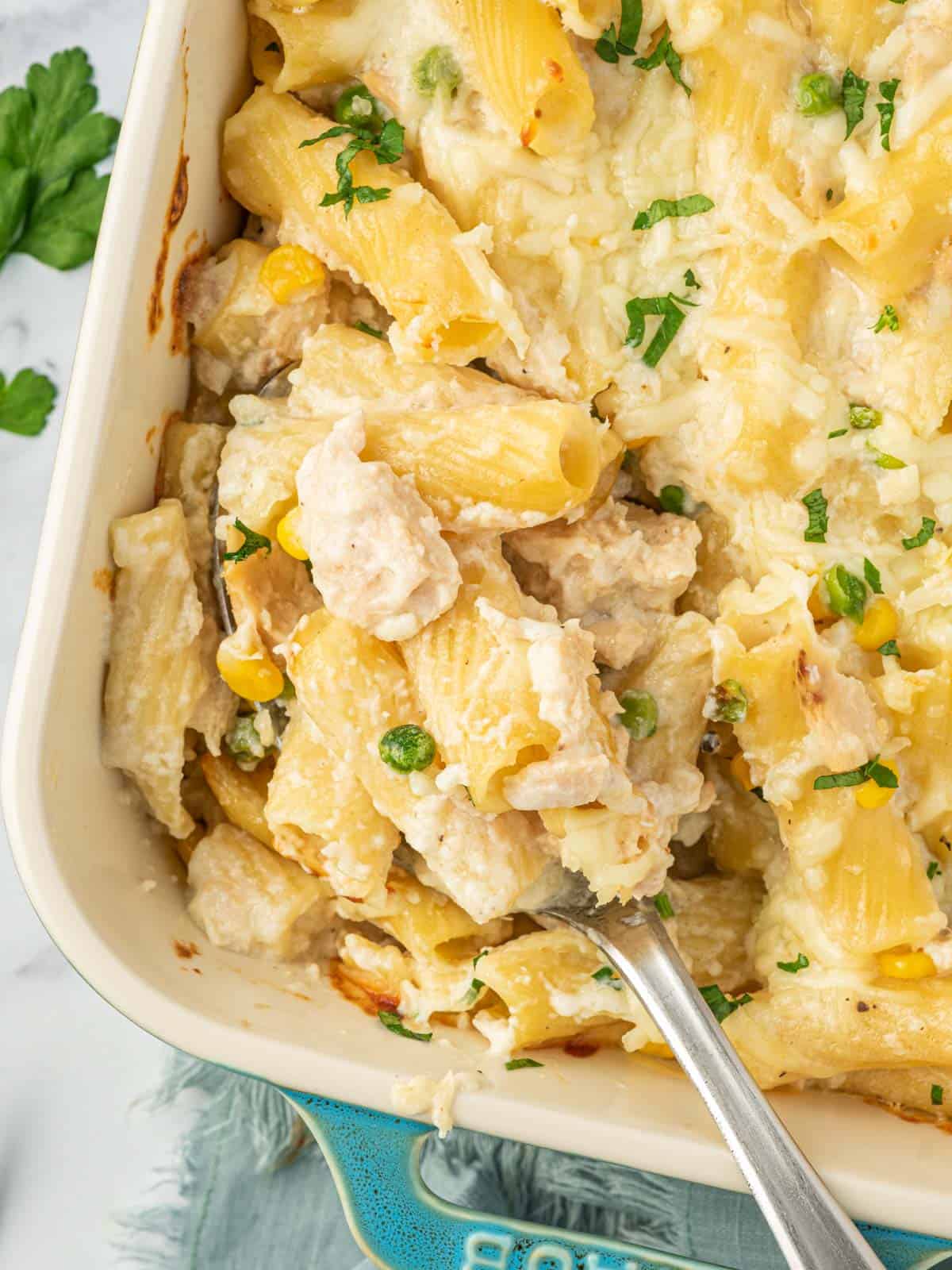 A spoon scoops a serving of cheesy tuna bake.