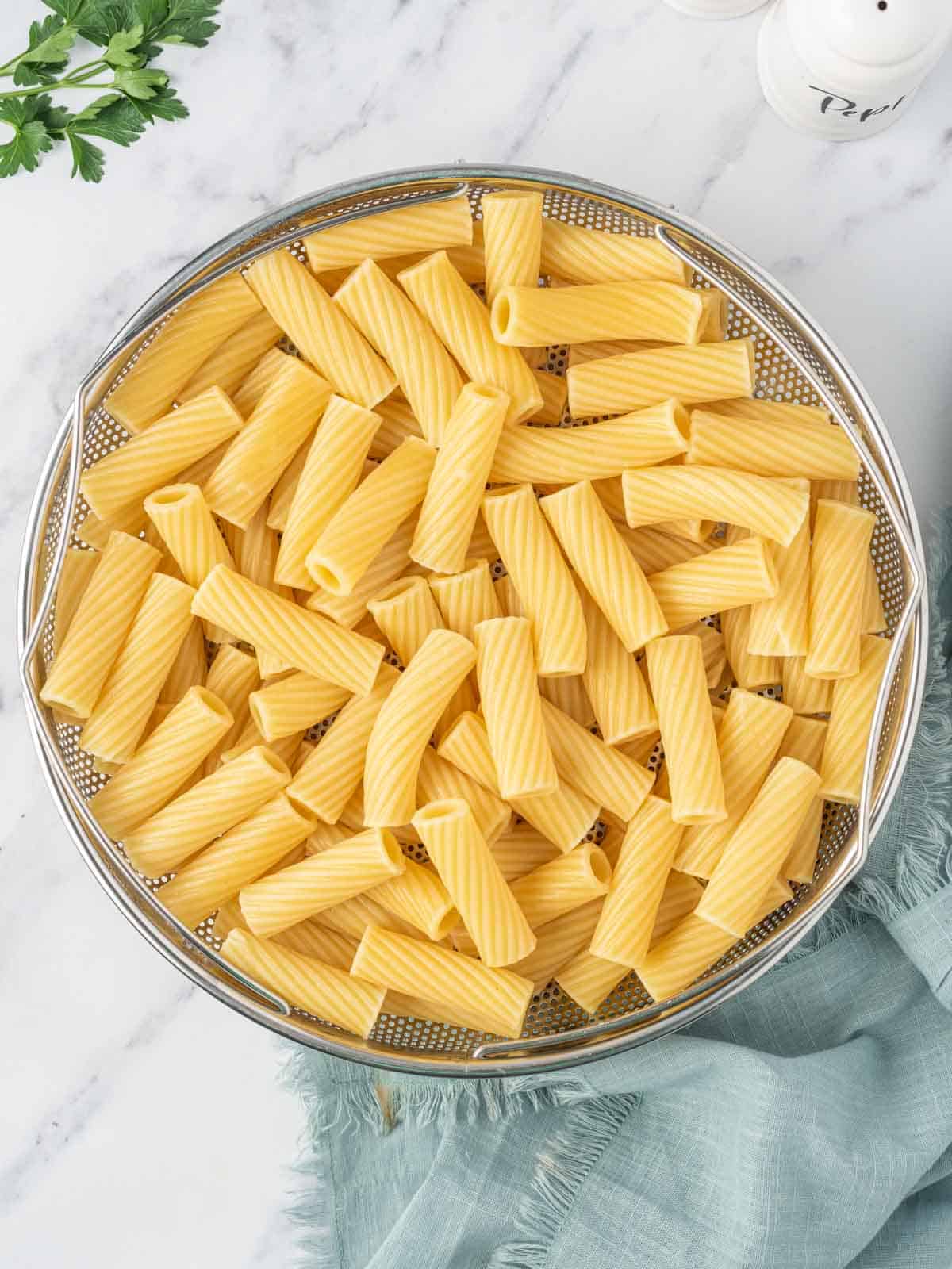 Cooked noodles in a colander.