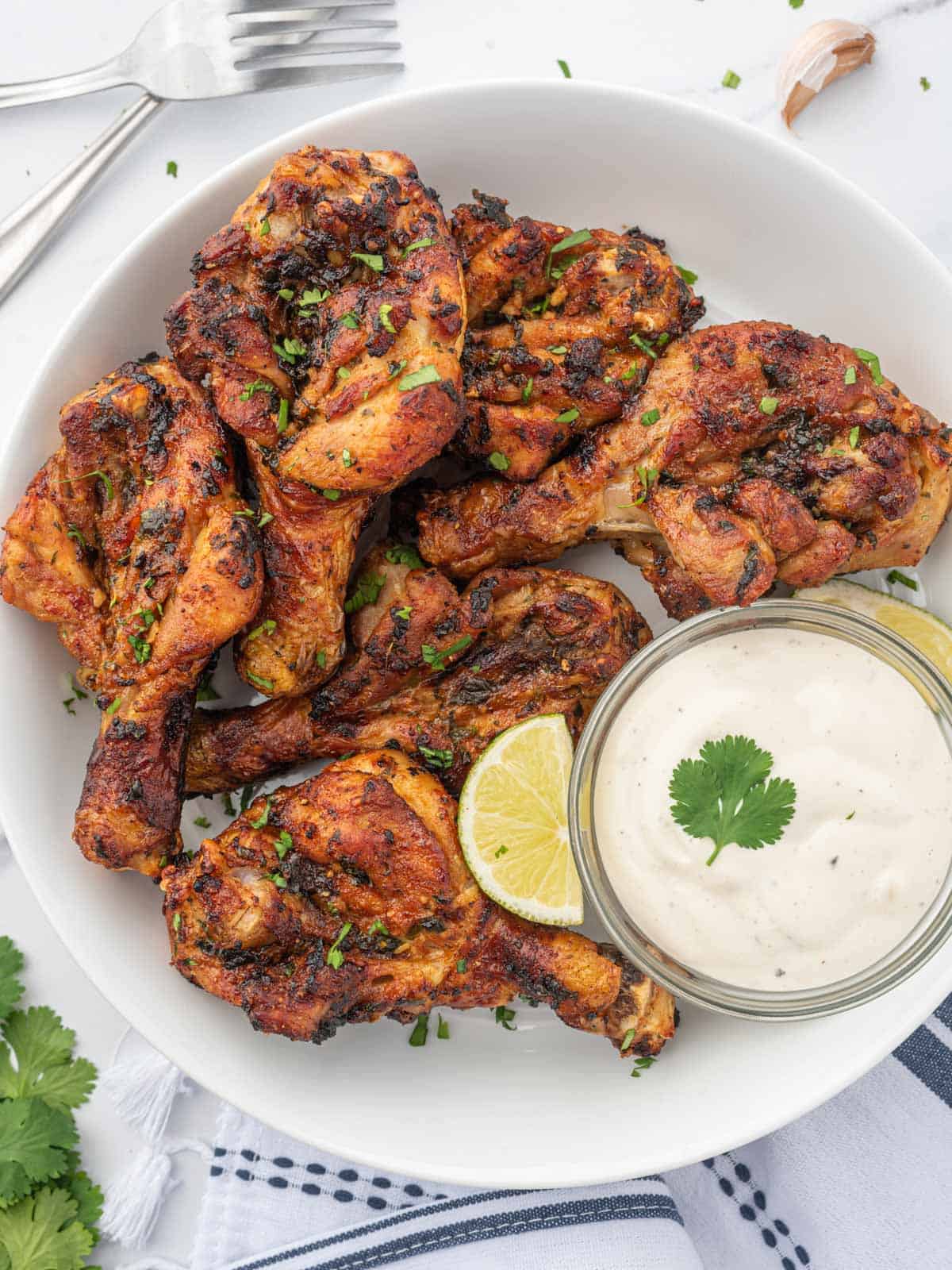 Butterfly drumsticks on a plate with a dipping sauce.