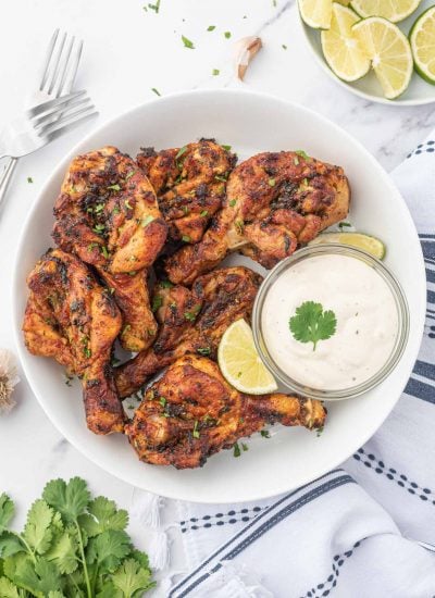 Air fryer butterfly chicken drumsticks on a plate with dipping sauce.