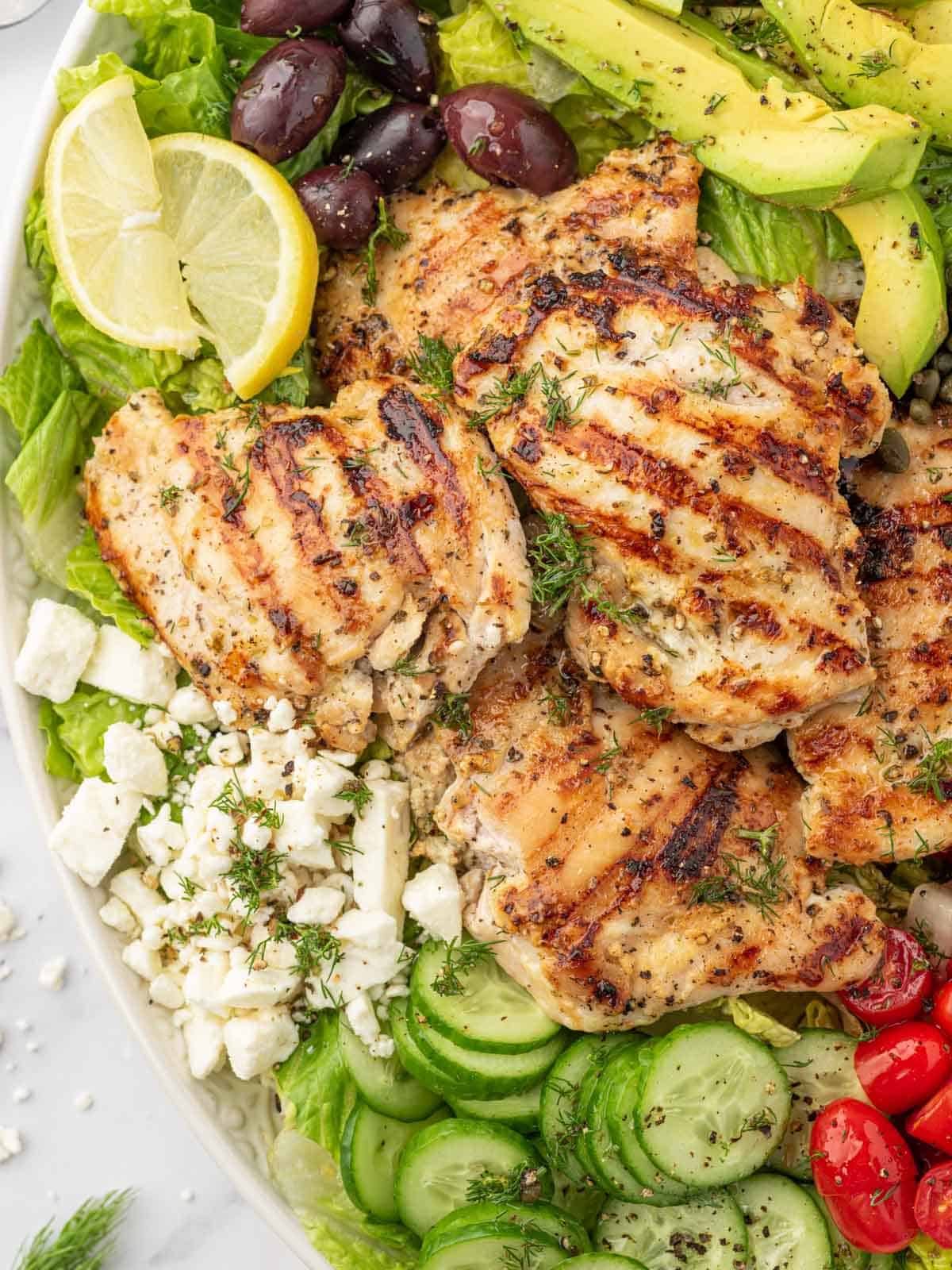 Close up of yogurt marinated grilled chicken on salad platter.