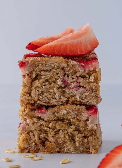 Healthy oatmeal strawberry bars stacked and topped with fresh strawberries.