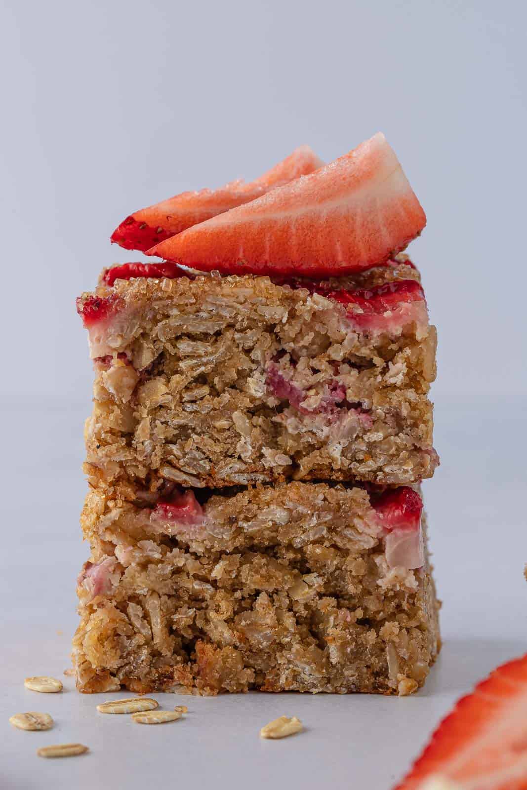 Healthy oatmeal strawberry bars stacked and topped with fresh strawberries.