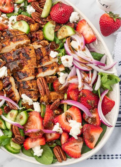 A serving platter with strawberry goat cheese salad and grilled chicken with balsamic dressing.