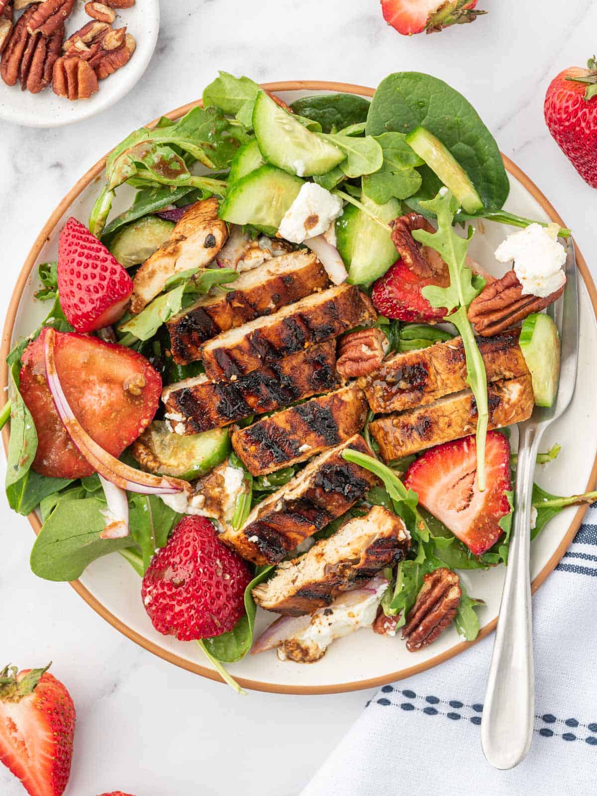 A serving plate of strawberry balsamic chicken salad with a fork.