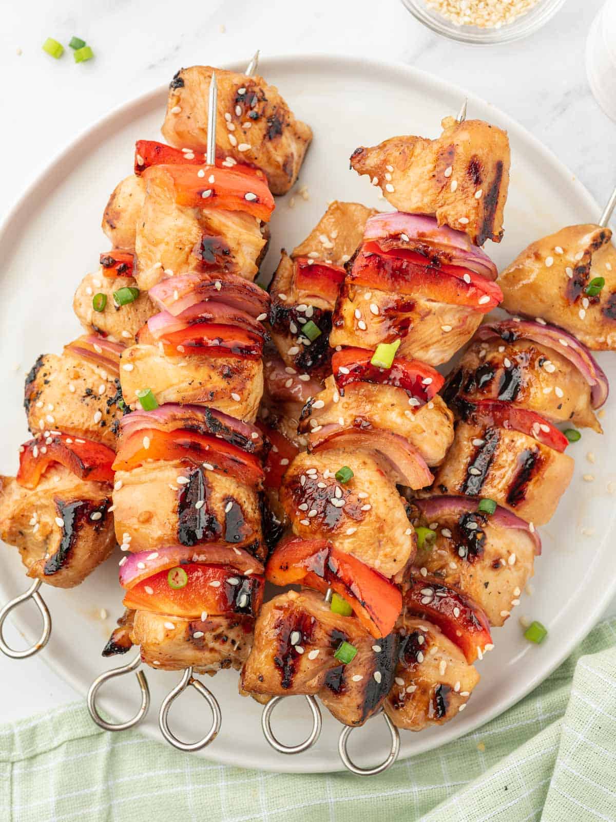 Chicken, red peppers and red onion grilled on skewers and placed on a platter.