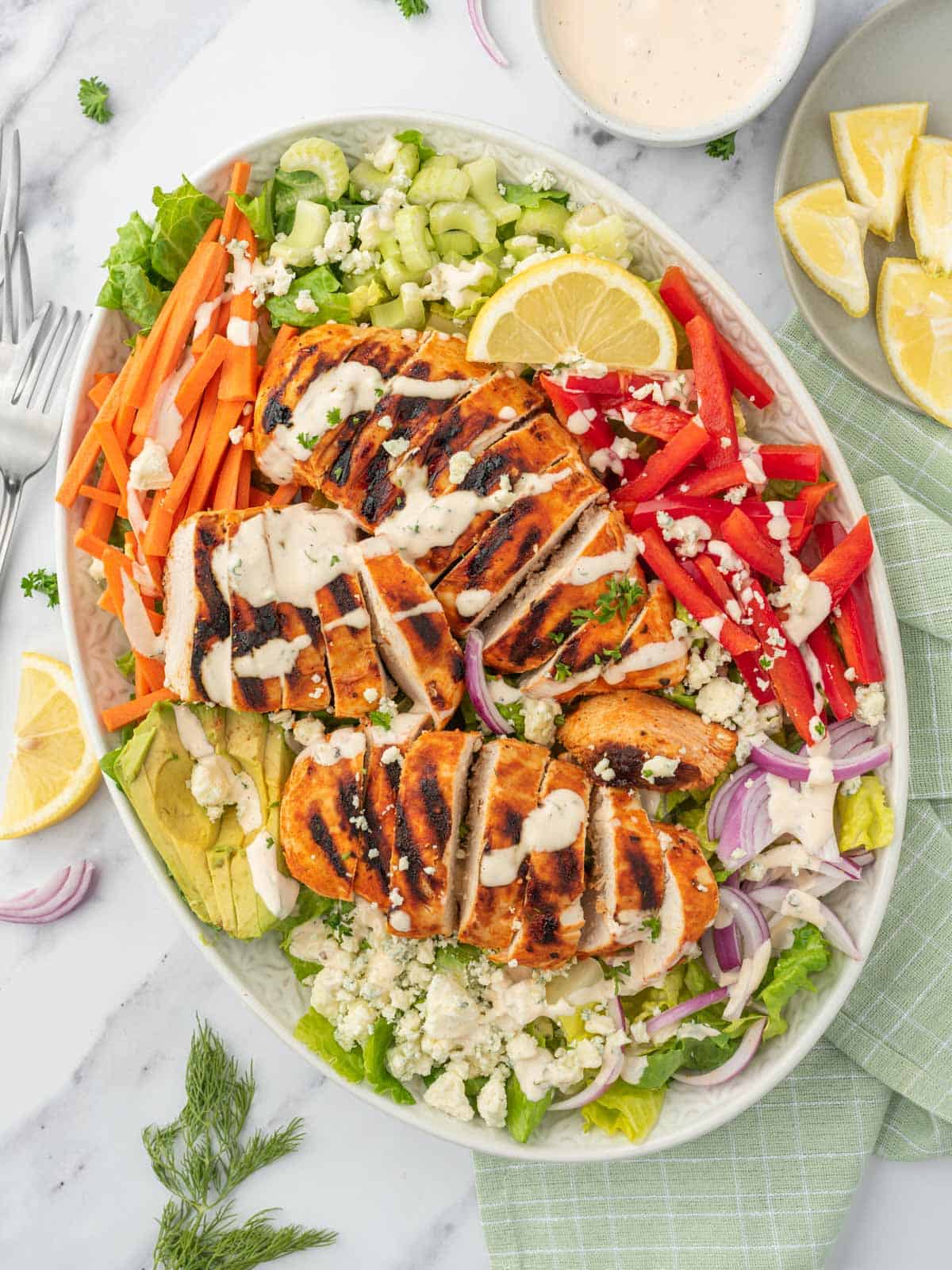 A platter of salad with buffalo chicken.
