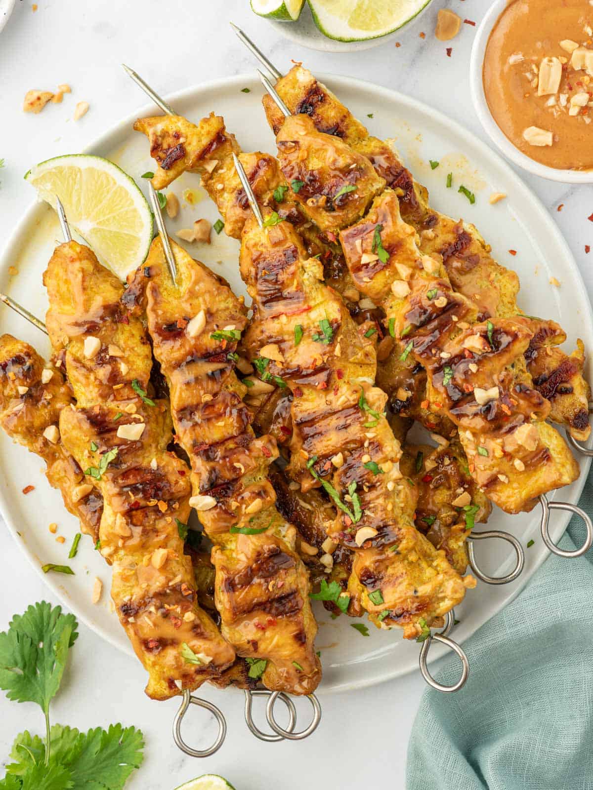 A pile of easy grilled chicken satay skewers on a platter.