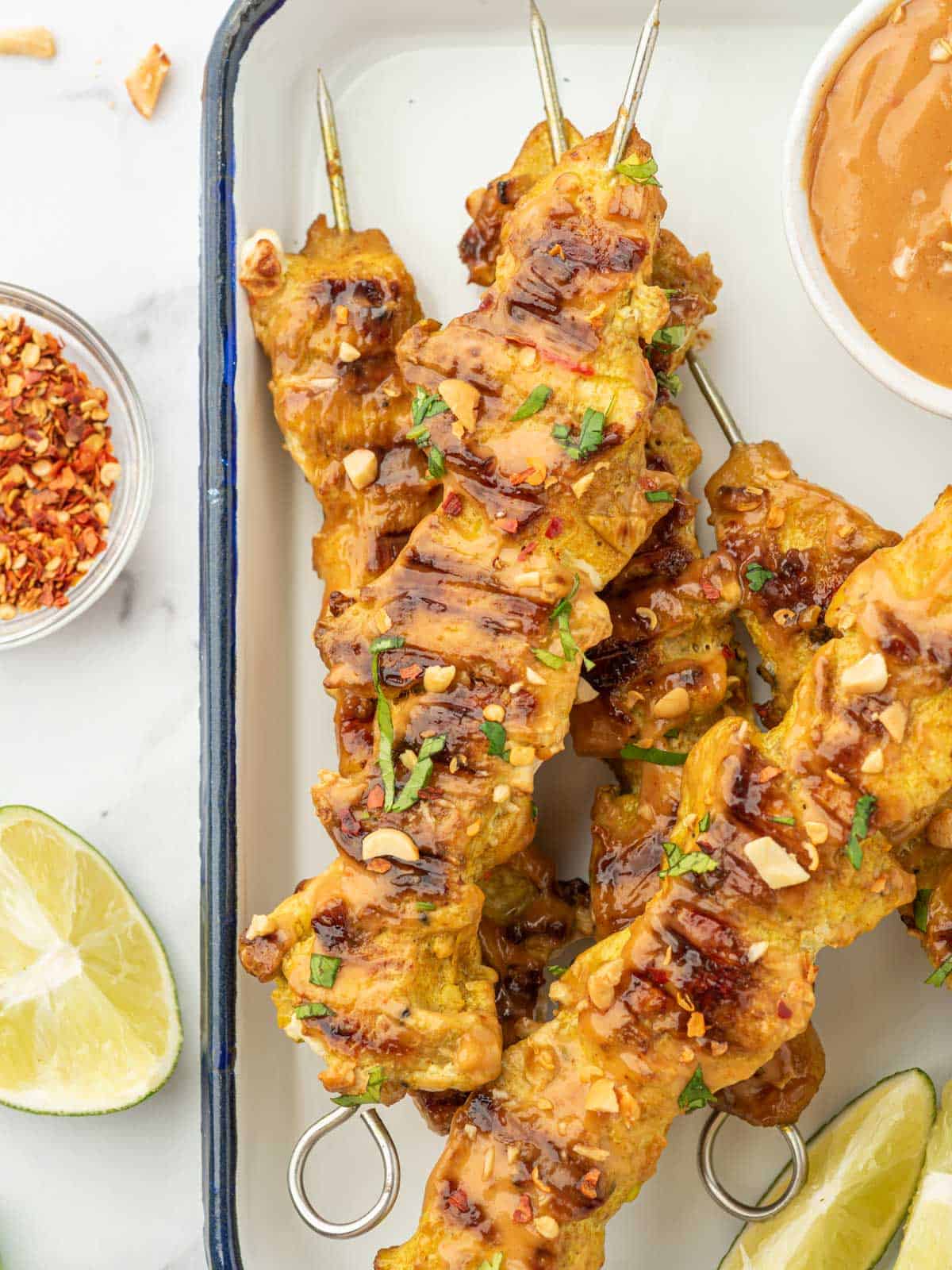 A serving tray with chicken satay skewers and peanut sauce for dipping.