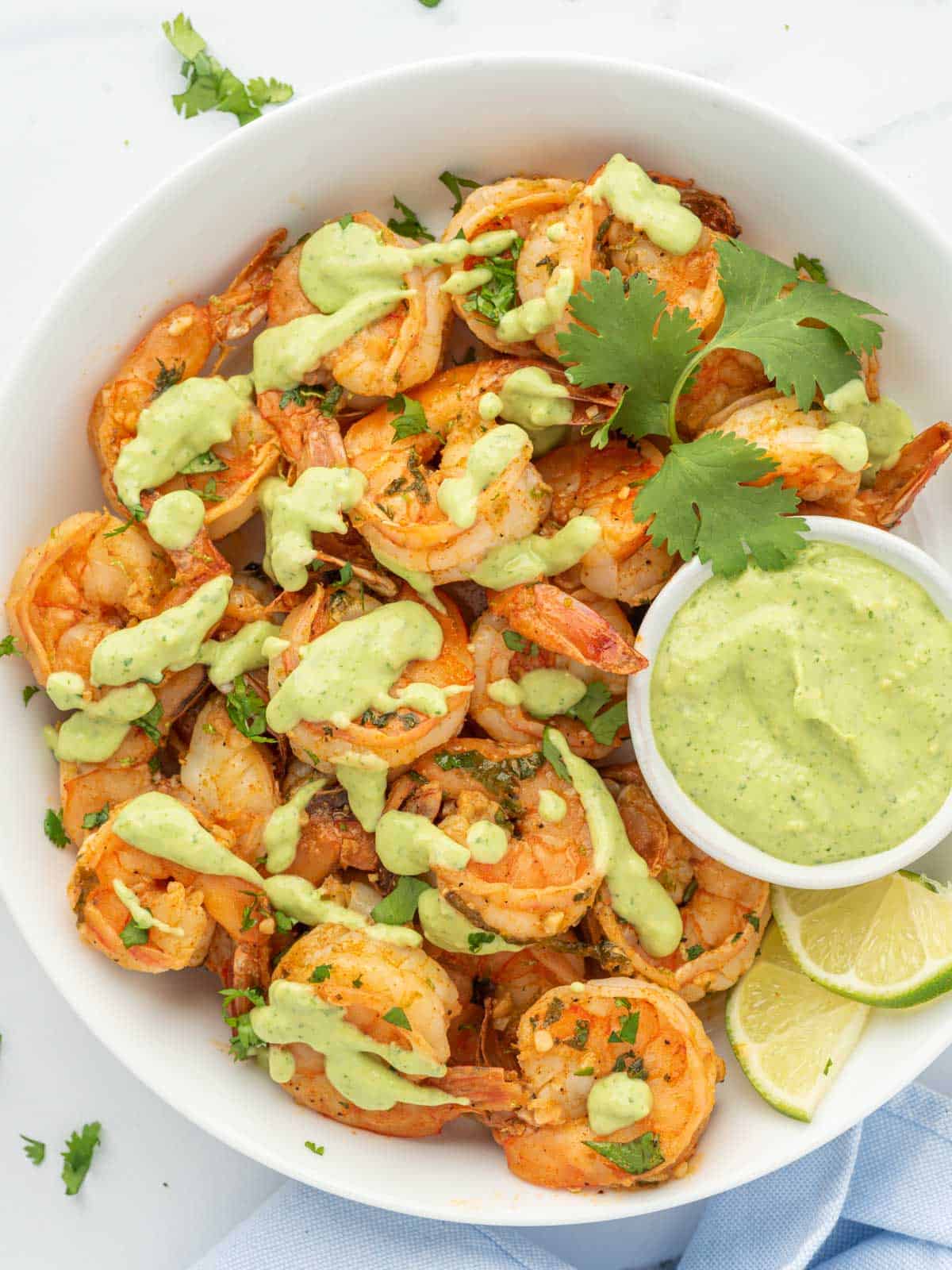 Chili powder shrimp in serving bowl drizzled with aioli.
