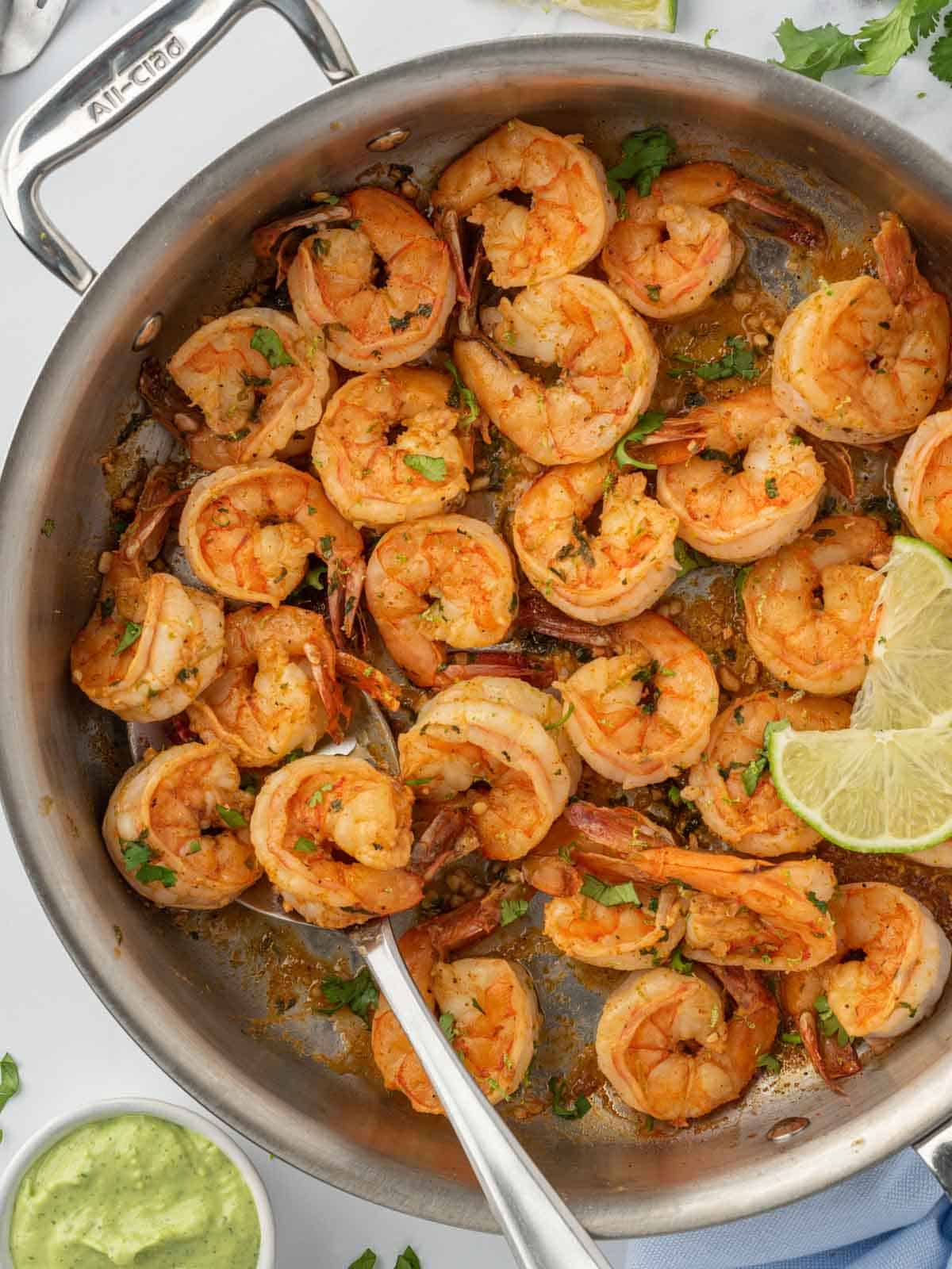 Sautéing shrimp with cilantro and lime in a pan.