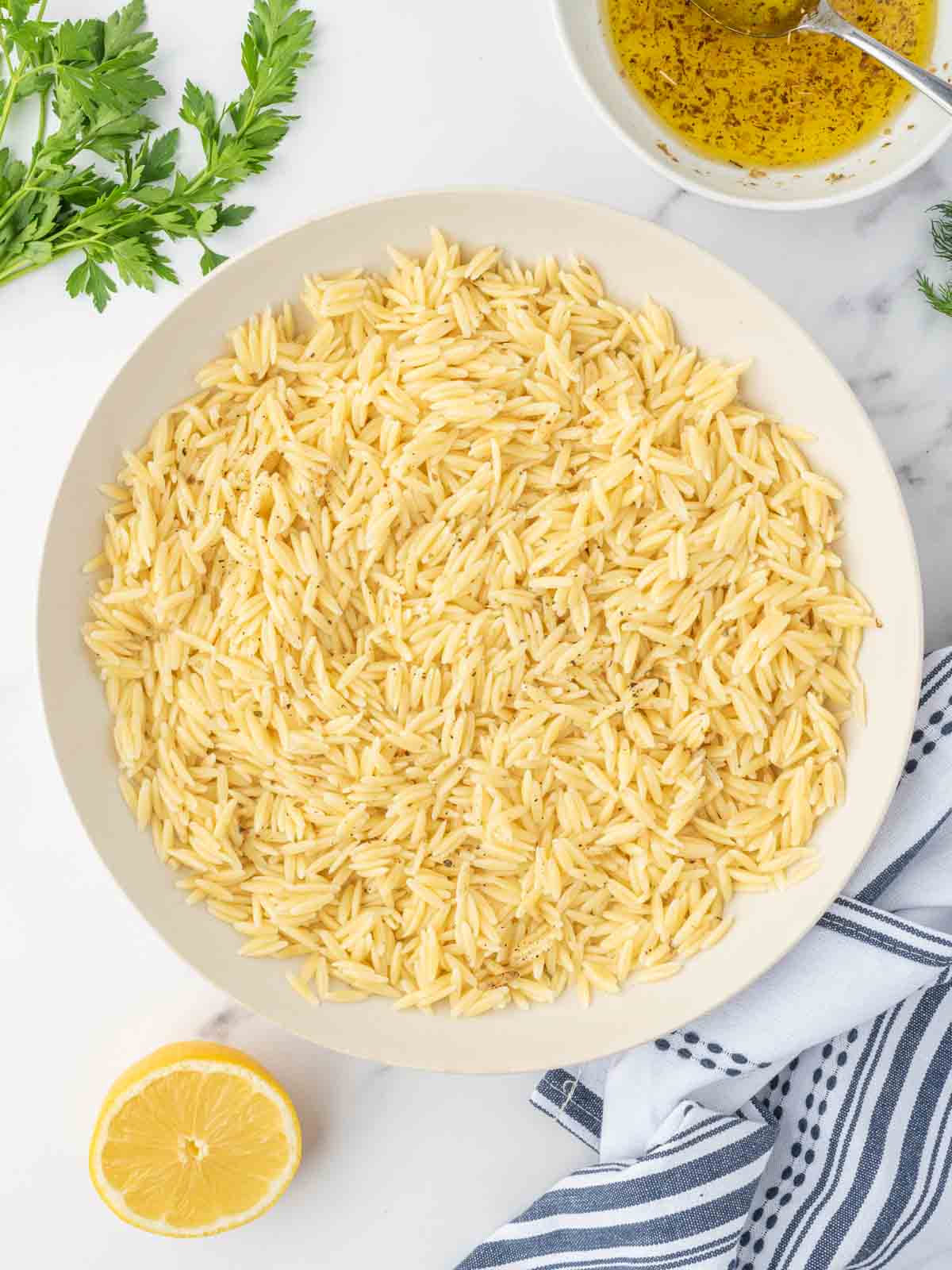 Cooked orzo being cooled in a bowl to add to mediterranean salad.