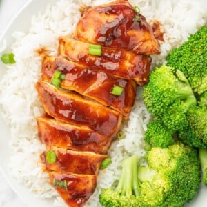 Sliced bbq chicken breast on a bed of rice with broccoli.