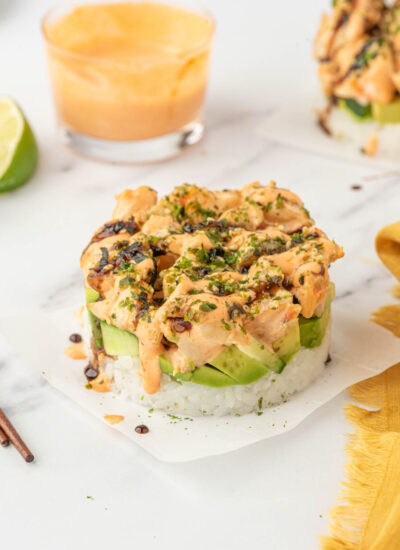 A shrimp sushi stack topped with furikake sits on parchment paper.