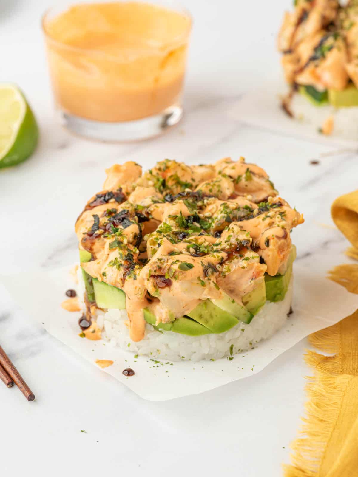A shrimp sushi stack topped with furikake sits on parchment paper.