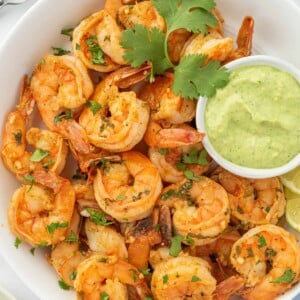 Chili lime shrimp in a serving bowl with green aioli for dipping.