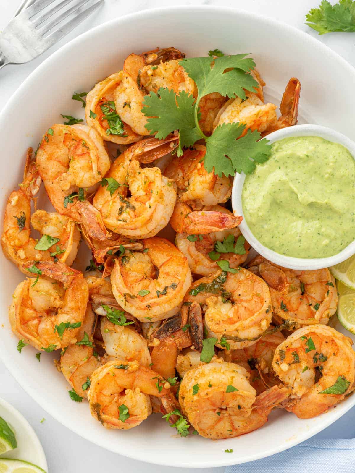 Chili lime shrimp in a serving bowl with green aioli for dipping.