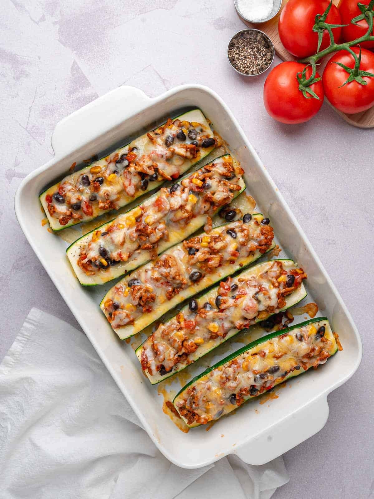 Baked zucchini boats with melted cheese, ground turkey, black beans, and corn.